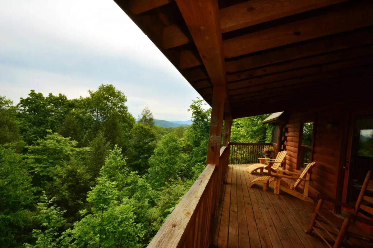 An exterior deck scene with classic wooden rocking chairs facing lush greenery and distant mountain views. The serene setup invites guests to step outside from the living room, feel the mountain breeze, and soak in the natural beauty right from home.