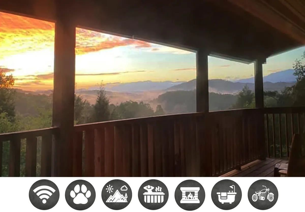 The image showcases the exterior of a cozy wooden cabin perched amidst the Smoky Mountains at sunset. A spacious deck with wooden railings overlooks a stunning mountain range, while the warm glow of the setting sun bathes the scene in tranquil light. The deck invites guests to relax and savor nature, whether sipping drinks, watching the sunset together, or stargazing under the open sky.